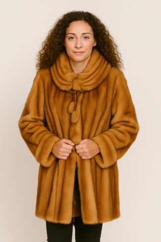 Whiskey mink stroller with pleated shawl collar and pom-pom tie closure, worn open.