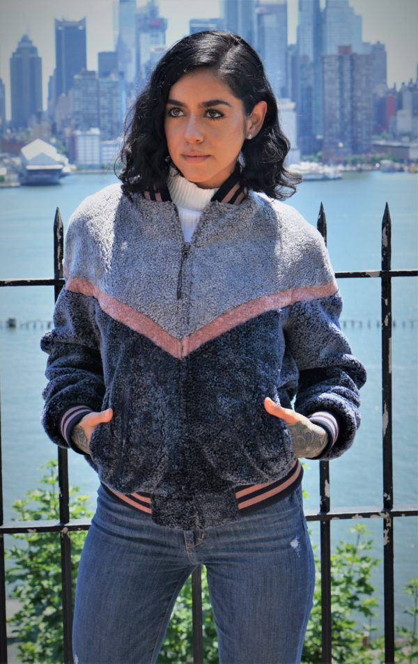 A woman wearing a jacket against a city landscape