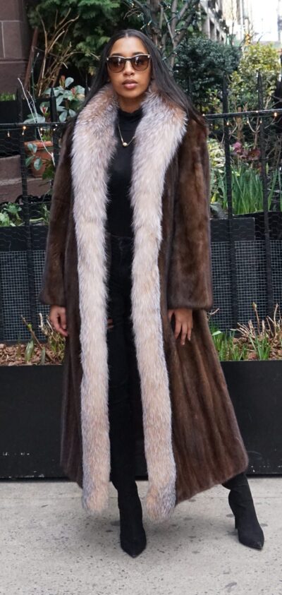 Full-length demi mink coat with crystal fox tuxedo trim worn open outdoors.