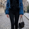 A model wearing a vibrant blue feathered fox fur jacket featuring a contrasting black fox fur tuxedo front and collar.