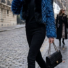 A model wearing a vibrant blue feathered fox fur jacket featuring a contrasting black fox fur tuxedo front and collar.