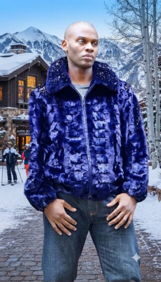 Model wearing a men's royal blue textured diamond-cut mink fur zip-up jacket with classic collar in a winter resort setting.